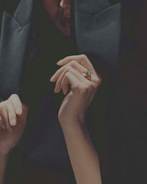 Close-up of hands with a diamond ring on a dark background
