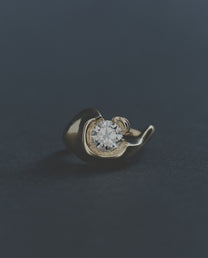 Gold ring with a round diamond on a dark background