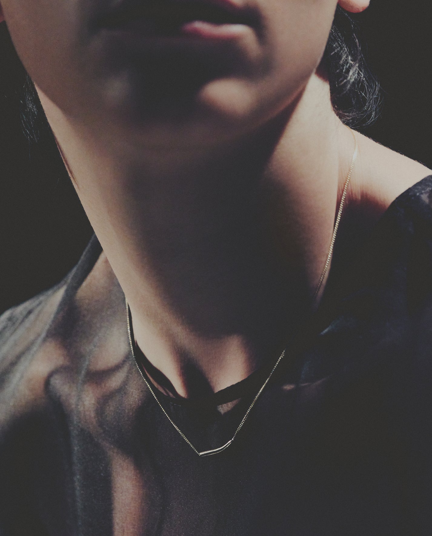 Close-up of a person wearing a necklace with a dark background