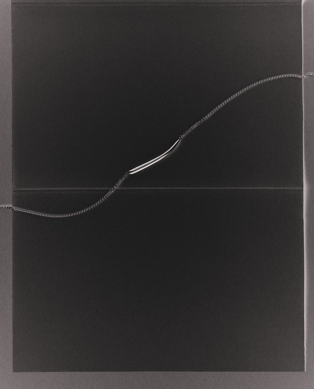 Black background with fine necklace running horizontally across it