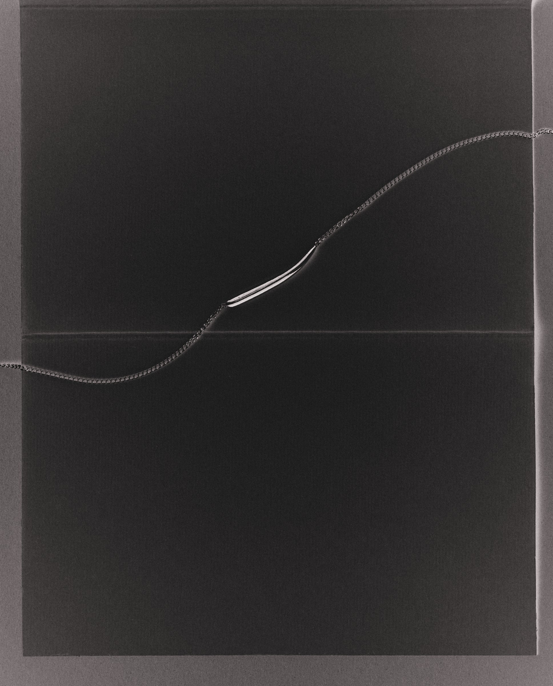 Black background with fine necklace running horizontally across it