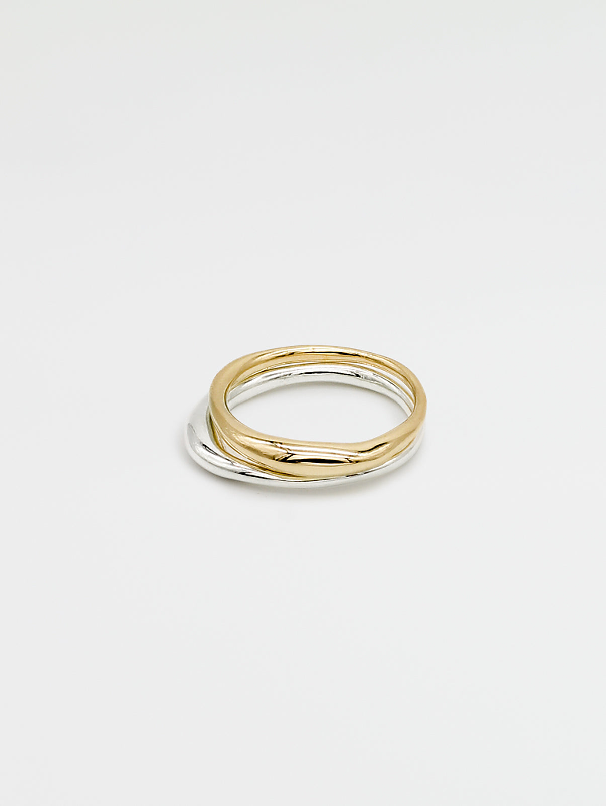 One silver and one gold band ring with a high shine finish, stacked on each other, showing the front view on a white background.