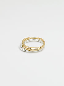 One silver and one gold band ring with a high shine finish, stacked on each other, showing the front view on a white background.
