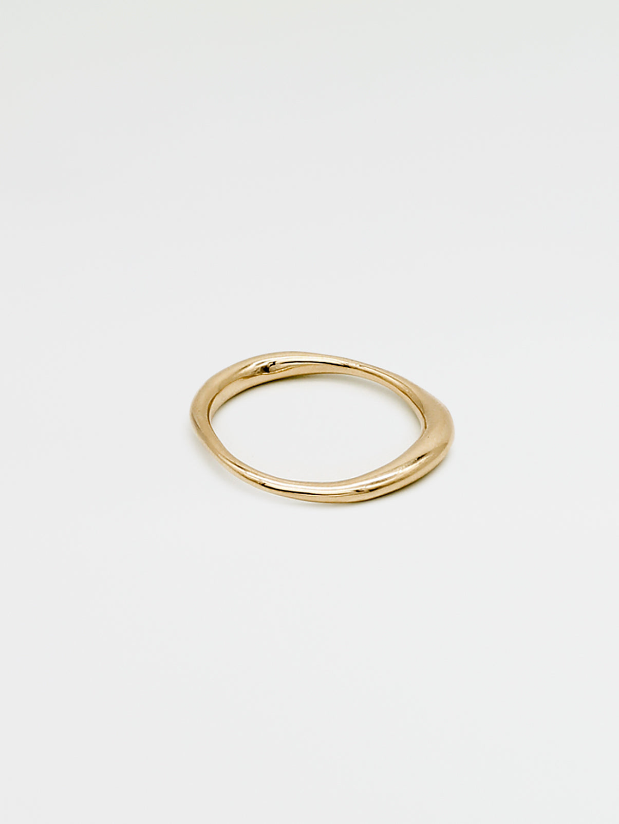 A single gold ring with an irregular band design, displayed against a white background.