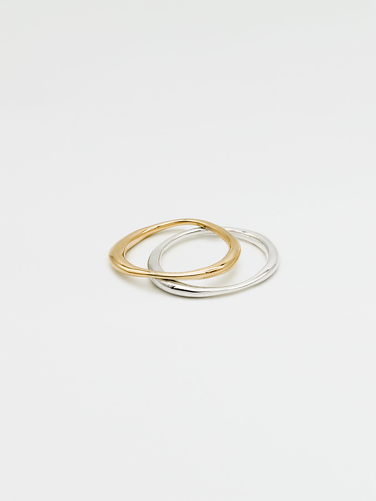 A single silver ring and single gold ring with an irregular band design, displayed against a white background.