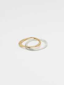 A single silver ring and single gold ring with an irregular band design, displayed against a white background.