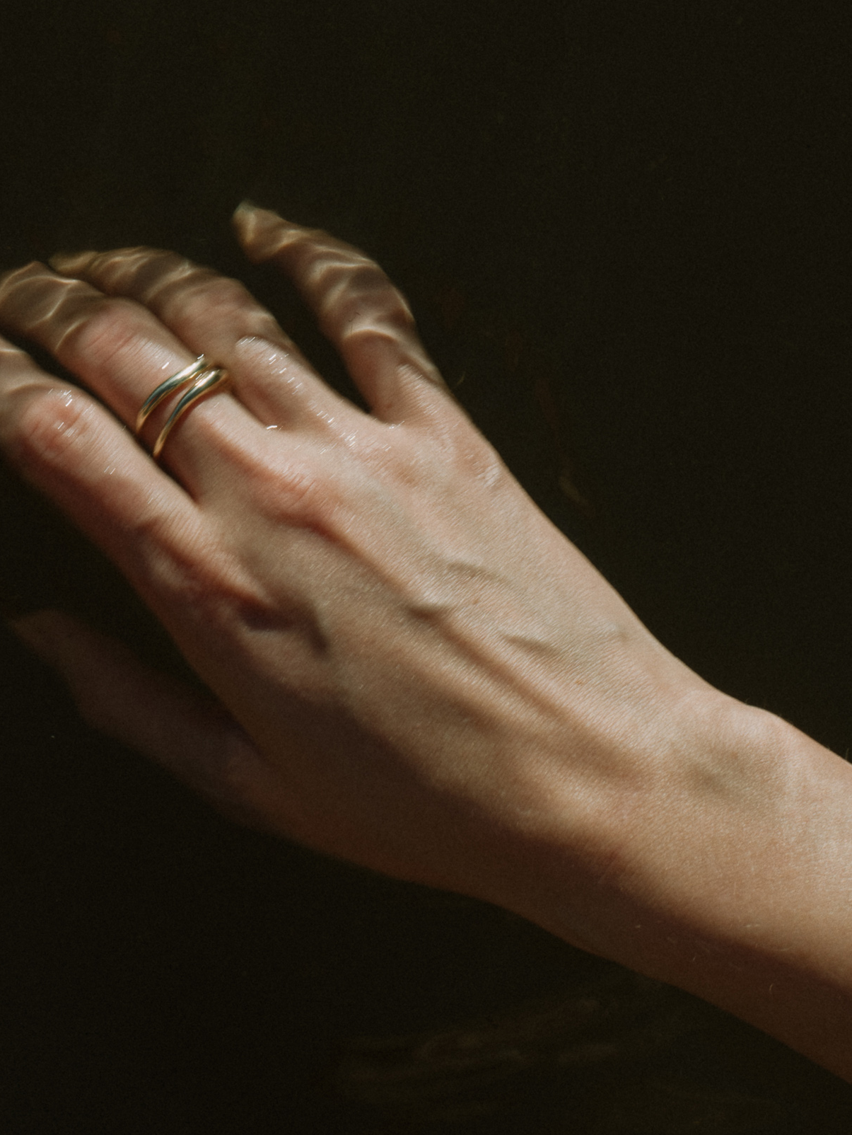 A fine gold ring with a carved, irregular design, displayed on a plain white background.