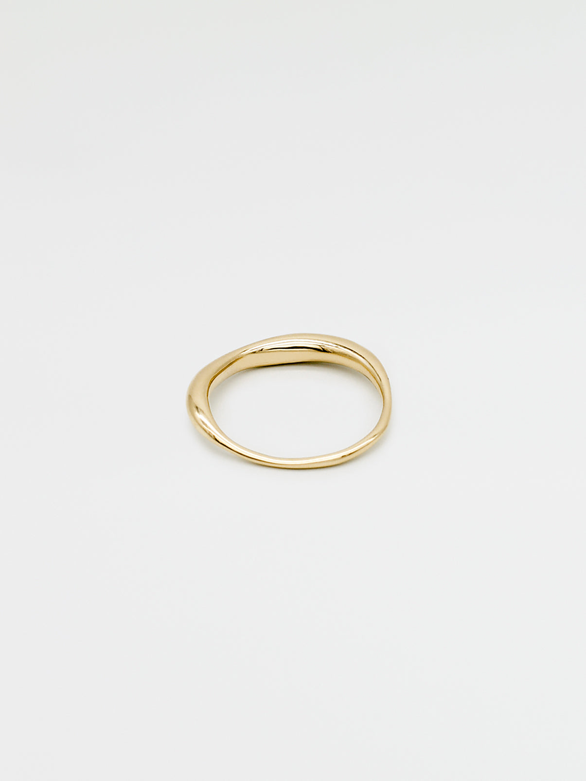 A fine gold ring with a carved, irregular design, displayed on a plain white background.