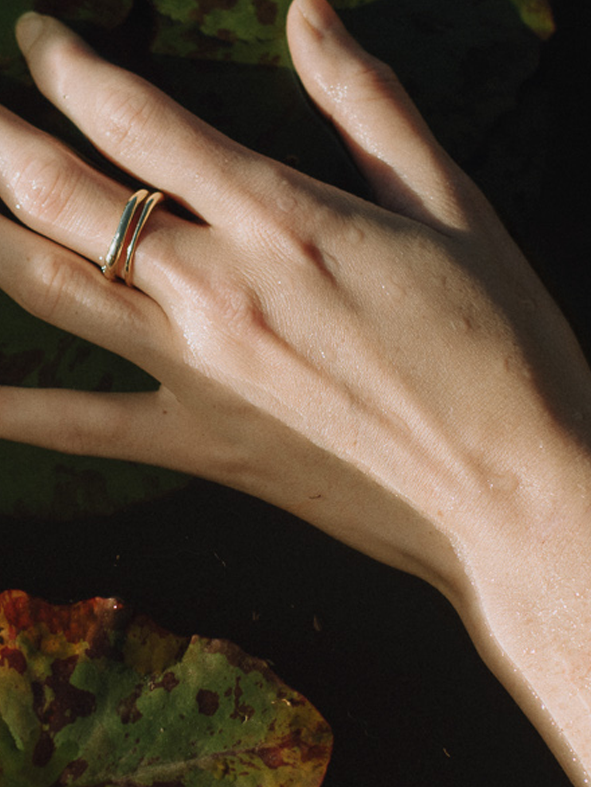 Close up of hand wearing two fine gold irregular rings