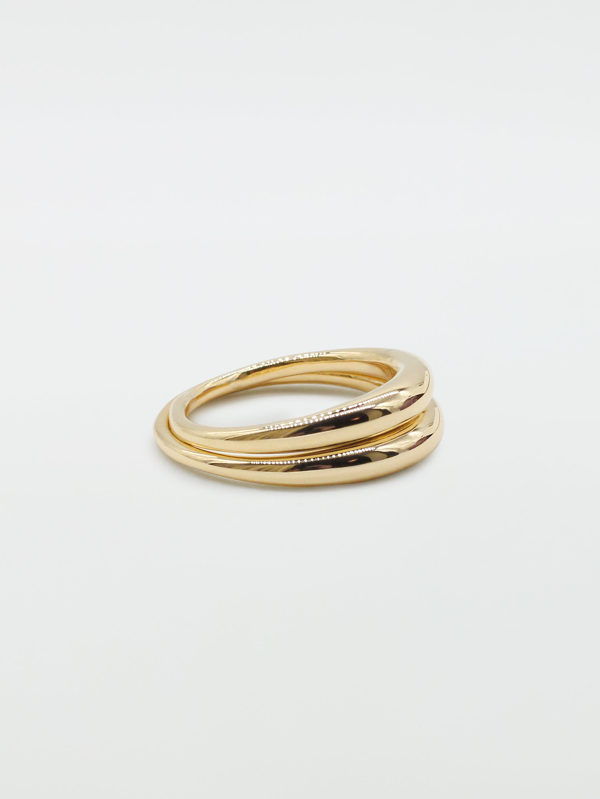Two bulbous gold rings stacked on top of each other on white background