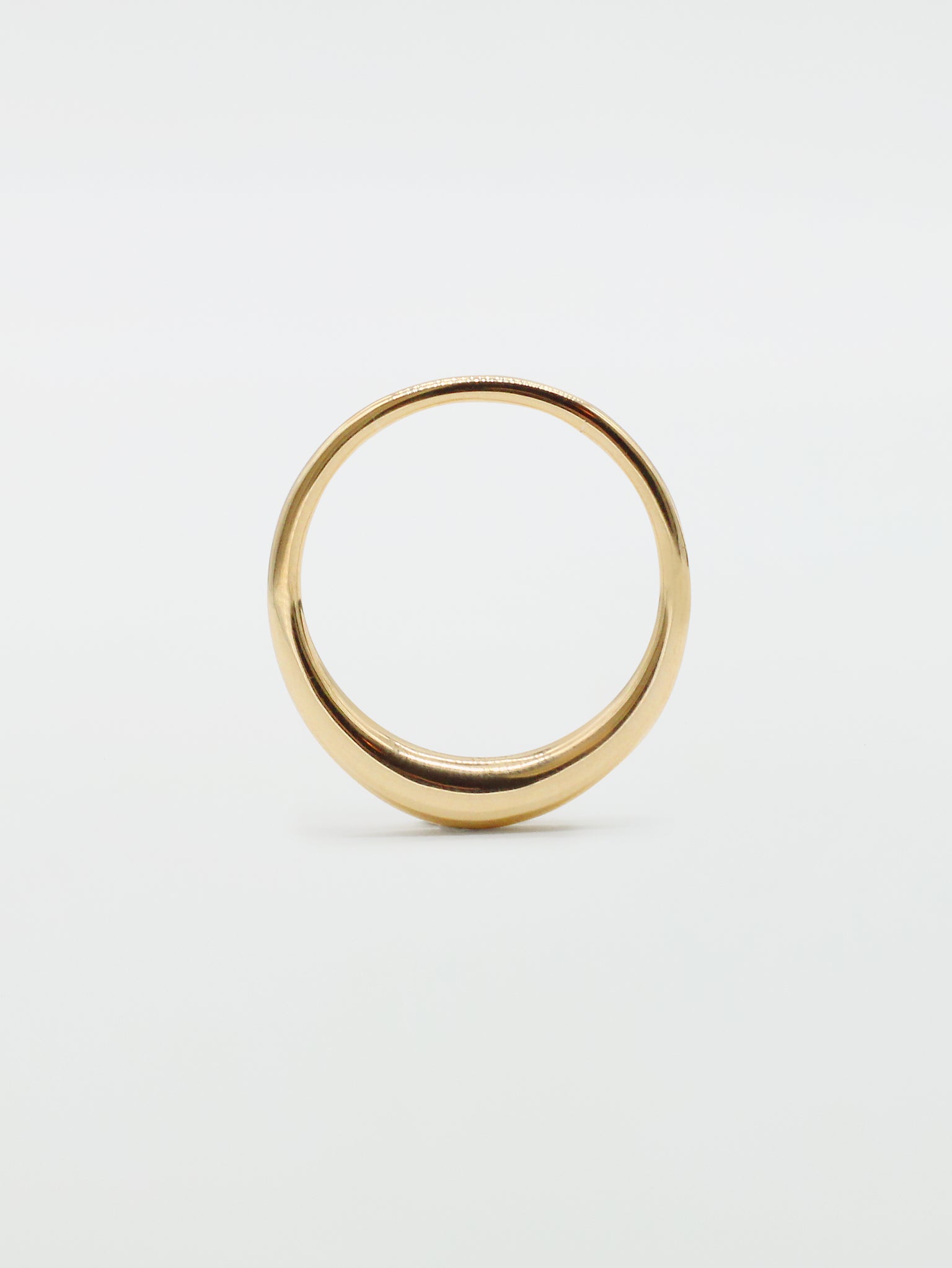 A simple band ring with a glossy finish, likely made of gold, shown on a white background.