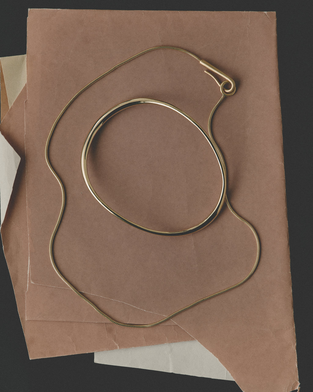 Gold necklace and bangle on brown paper