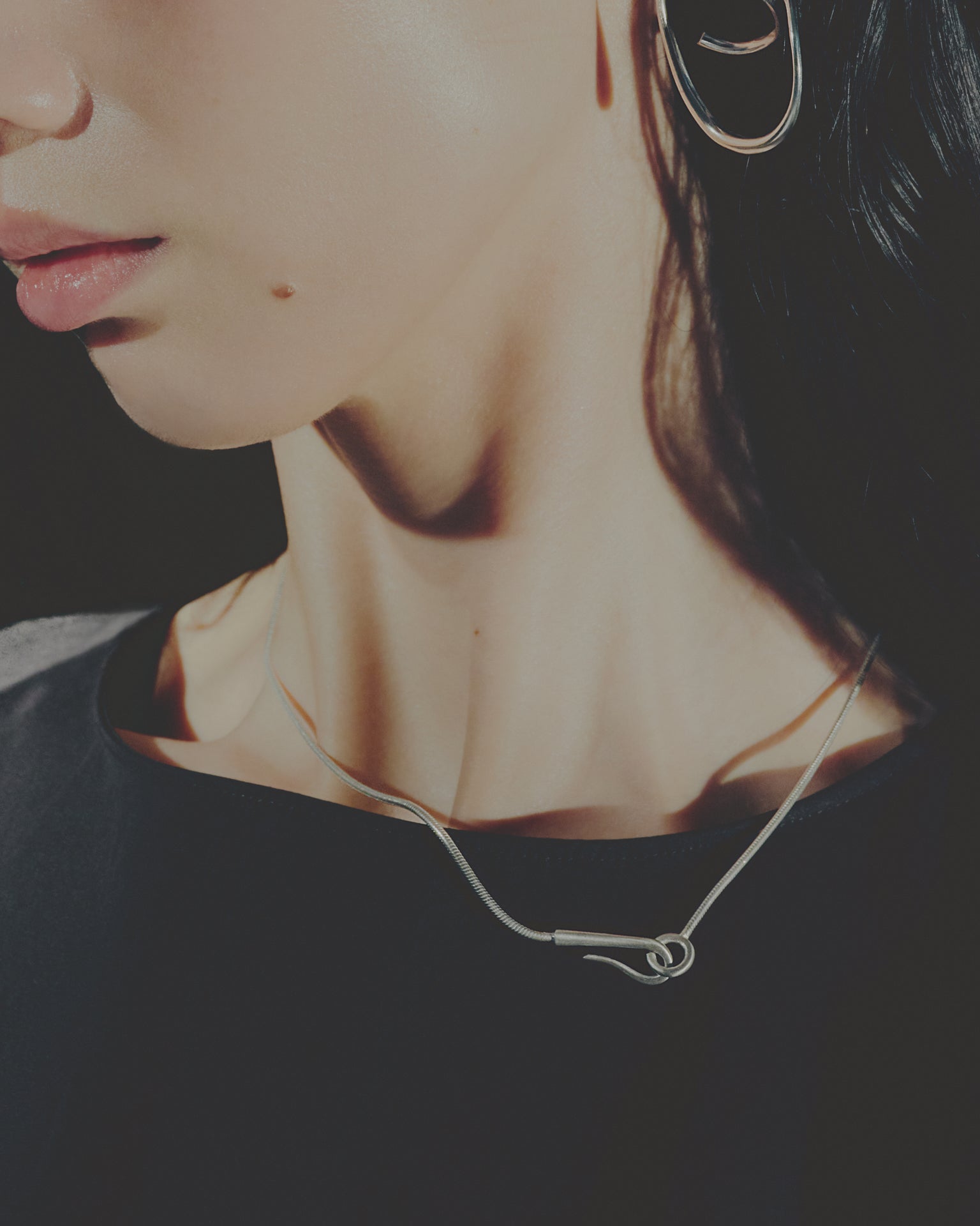 Close-up of a person wearing a necklace with a dark background