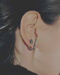 Close-up of an ear wearing a silver hoop earring with a small gemstone.