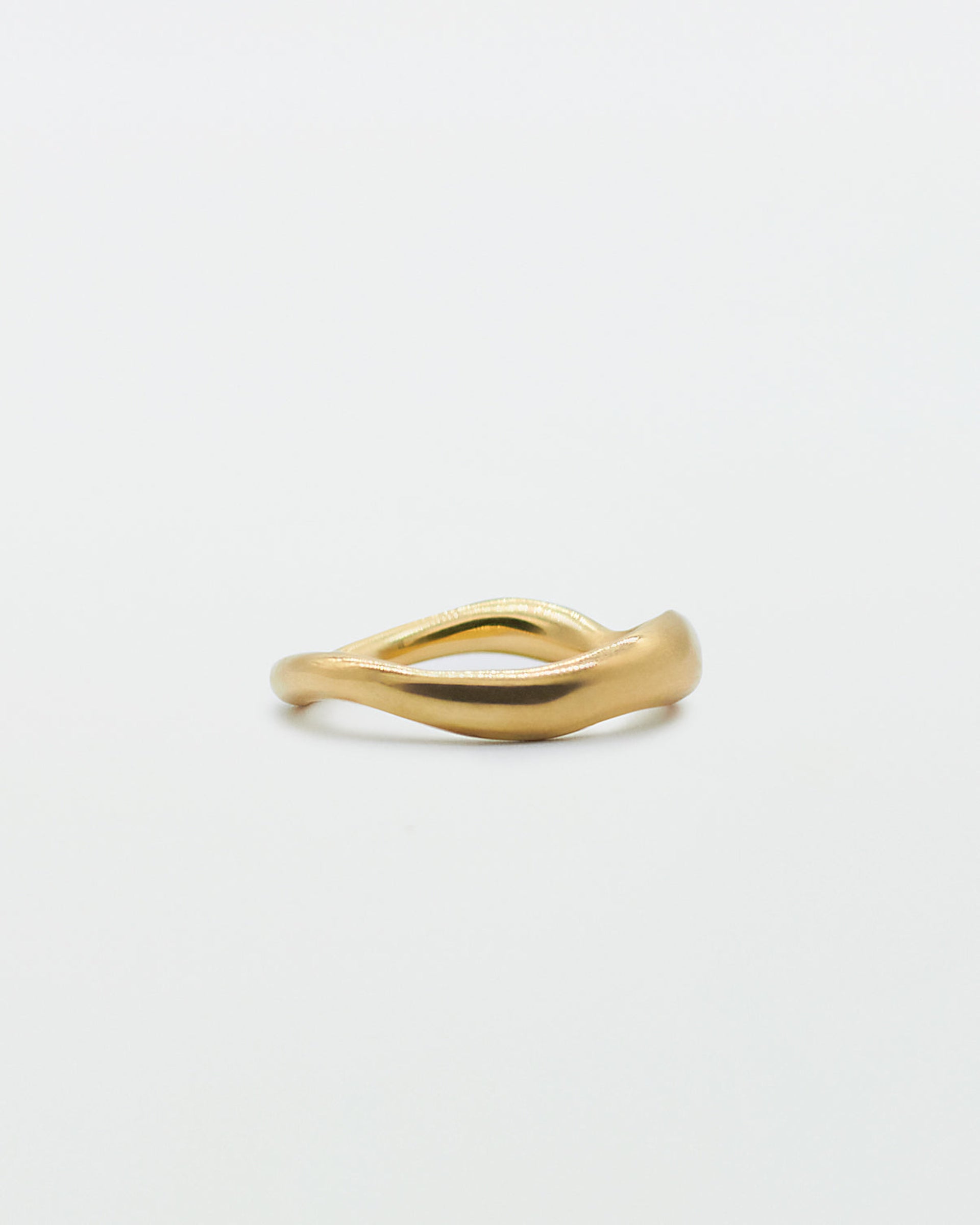 A gold band ring with a carved, irregular design on a plain white background.