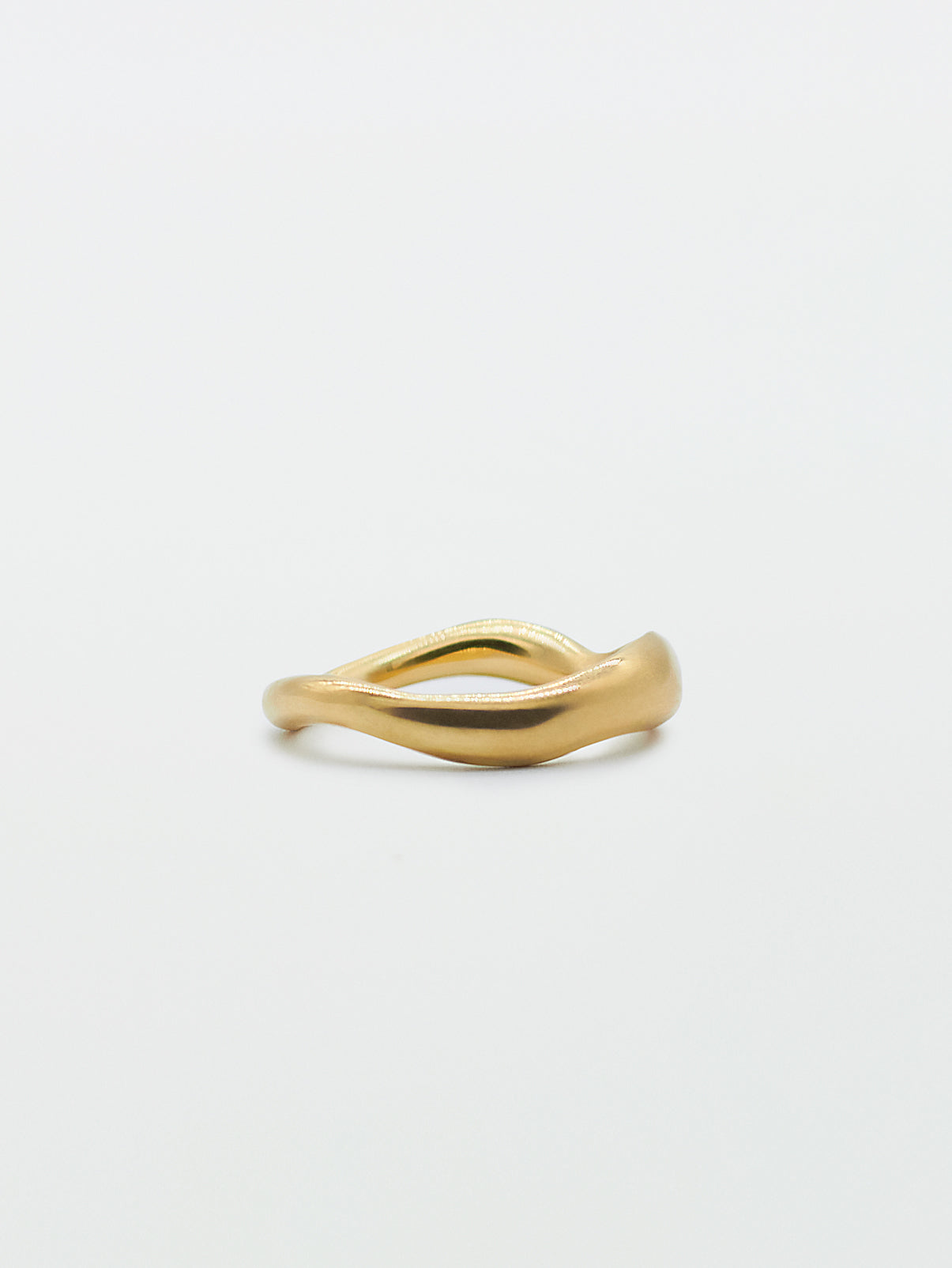 A gold band ring with a carved, irregular design on a plain white background.