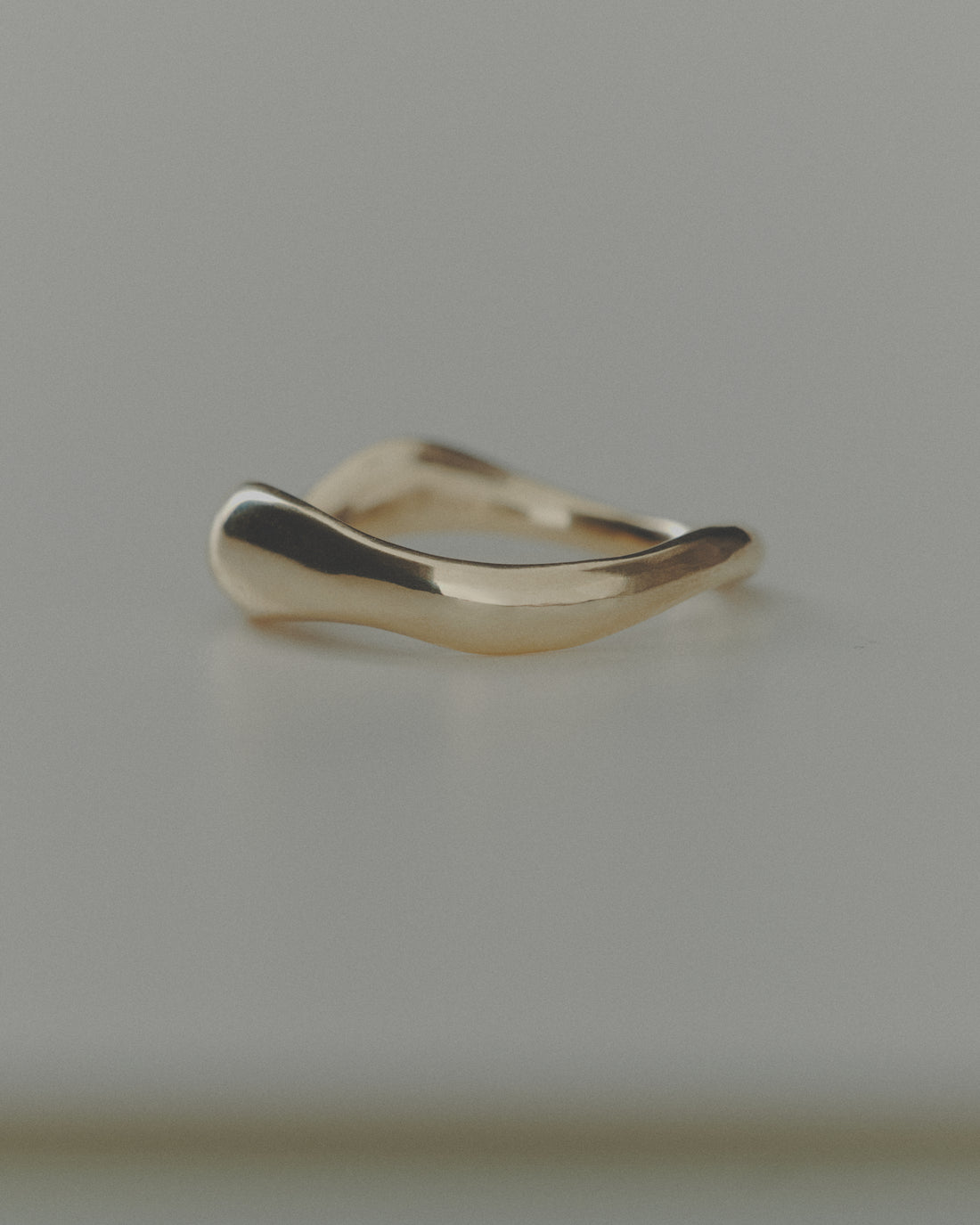 Gold ring with a wavy design on a gray background