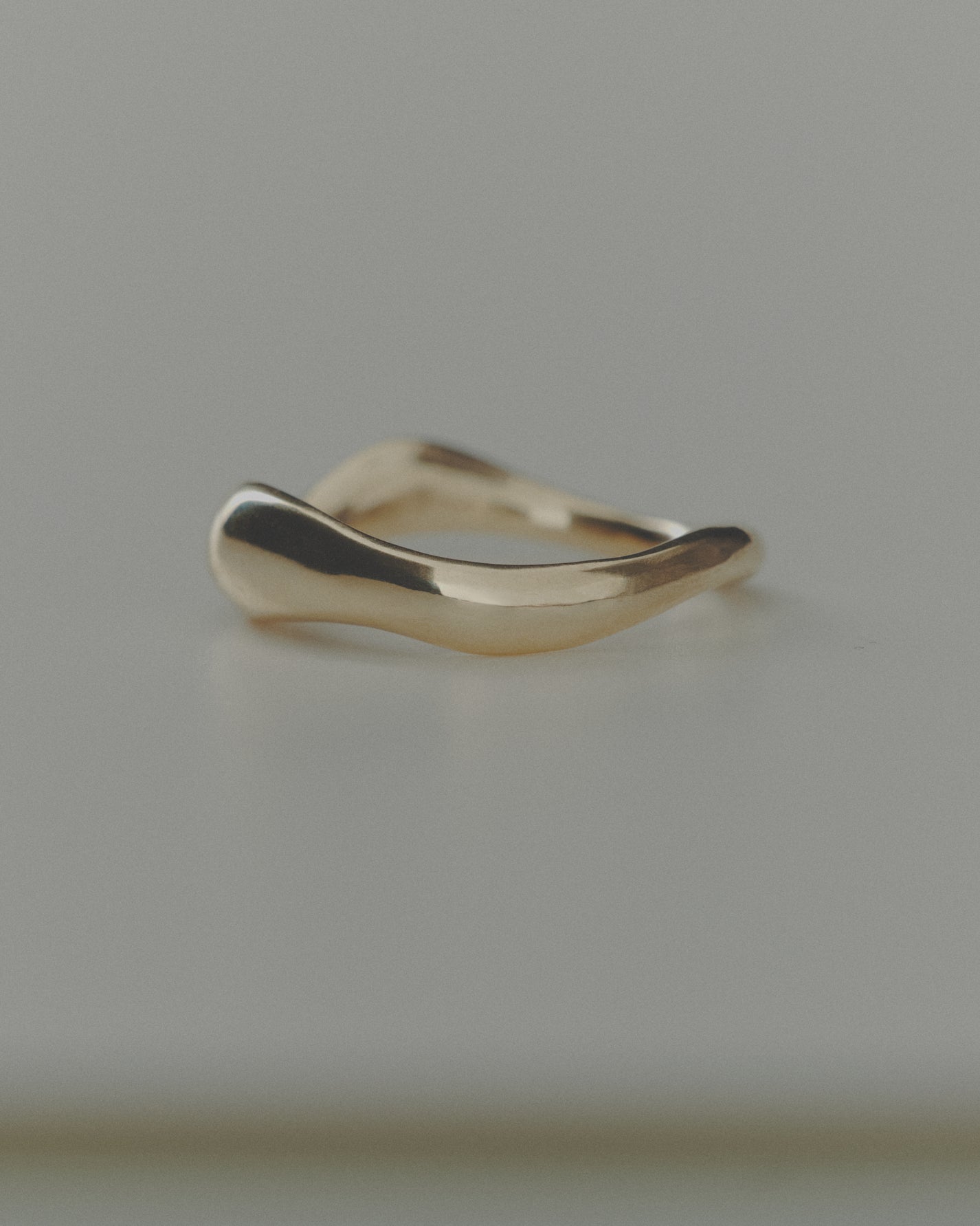 Gold ring with a wavy design on a gray background