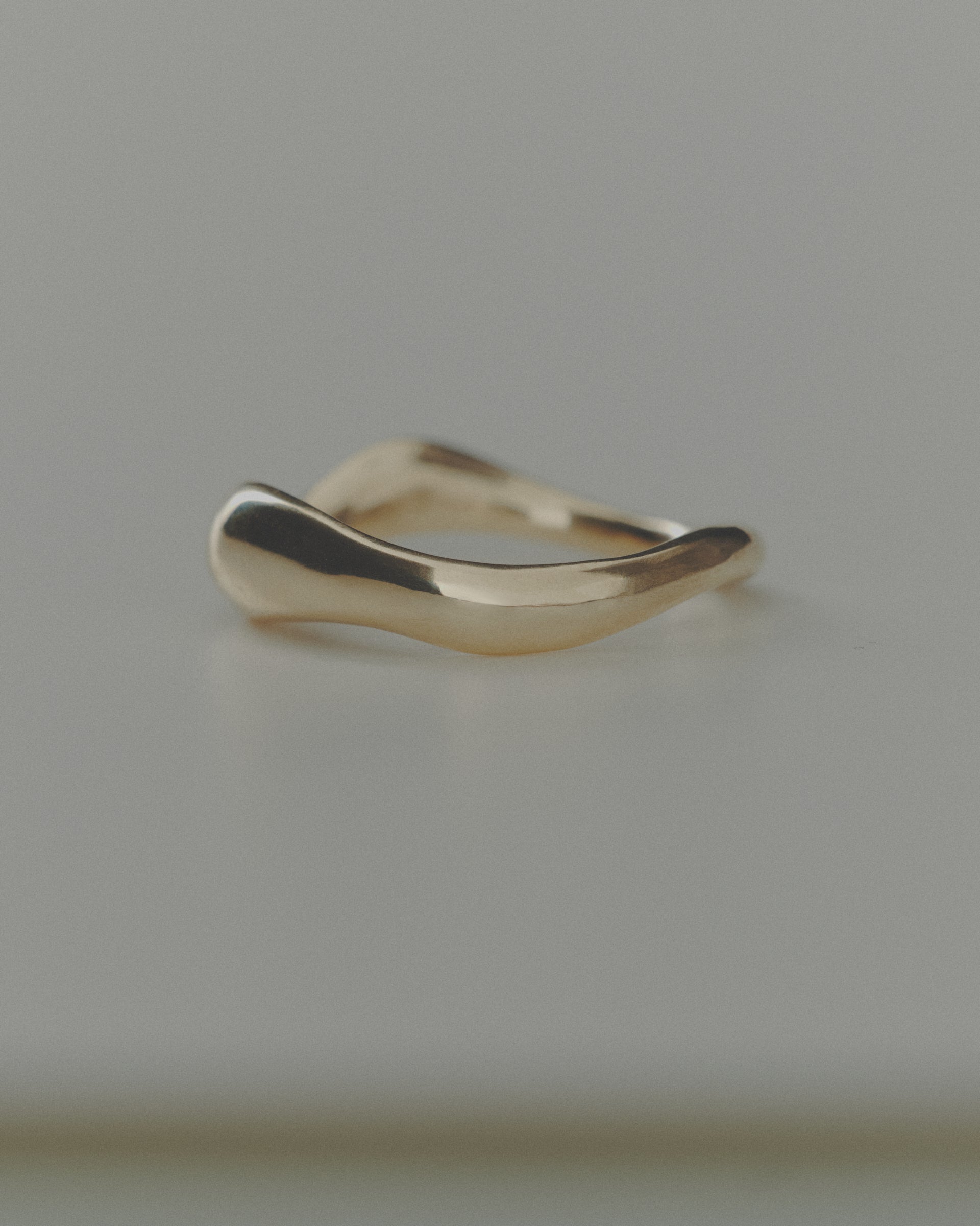 Gold ring with a wavy design on a gray background