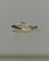 Gold ring with a wavy design on a gray background