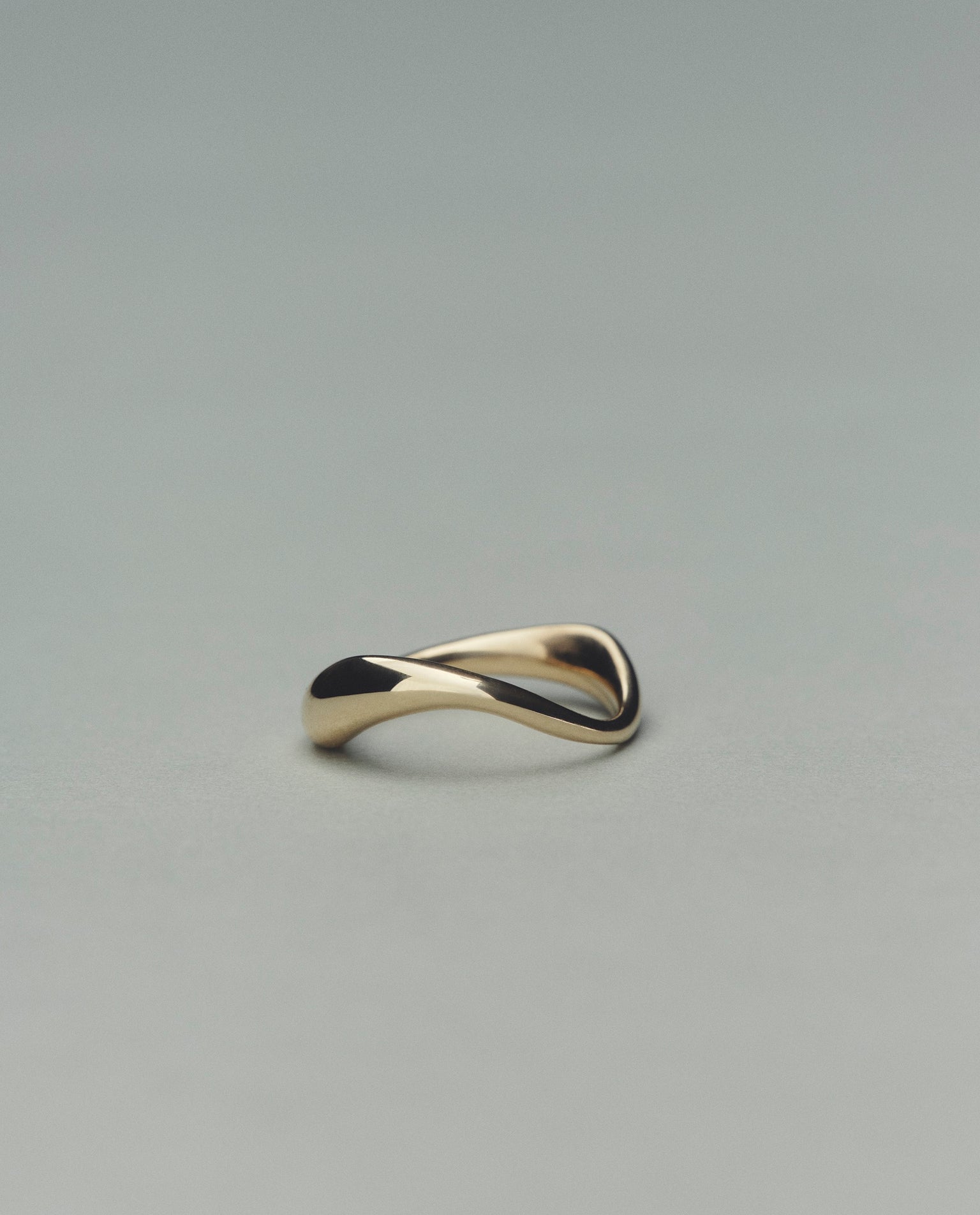 Gold ring with a wavy design on a gray background