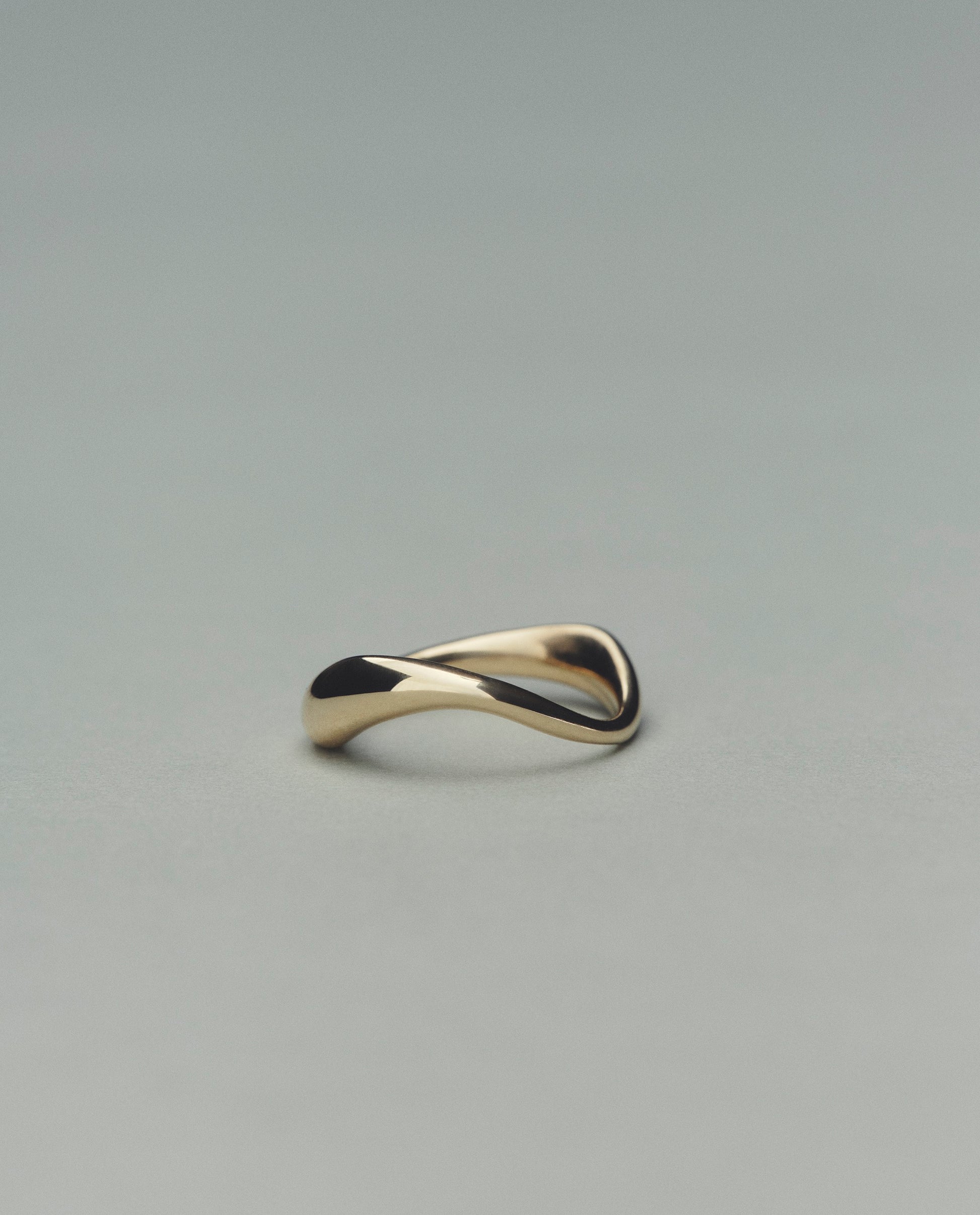 Gold ring with a wavy design on a gray background