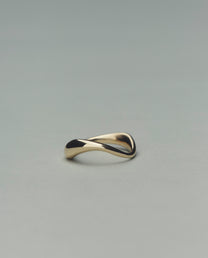 Gold ring with a wavy design on a gray background