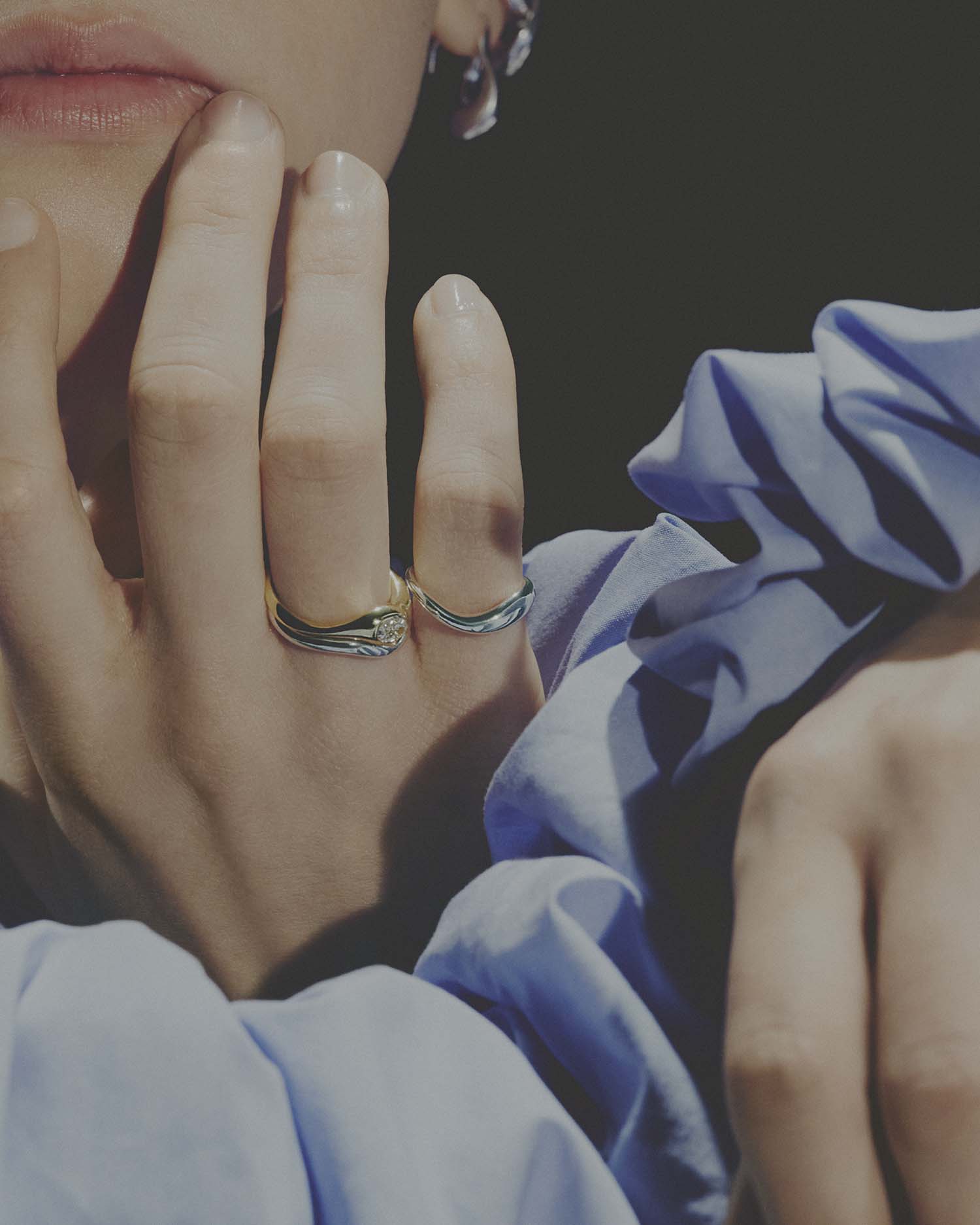 Close-up of a hand wearing rings on a dark background