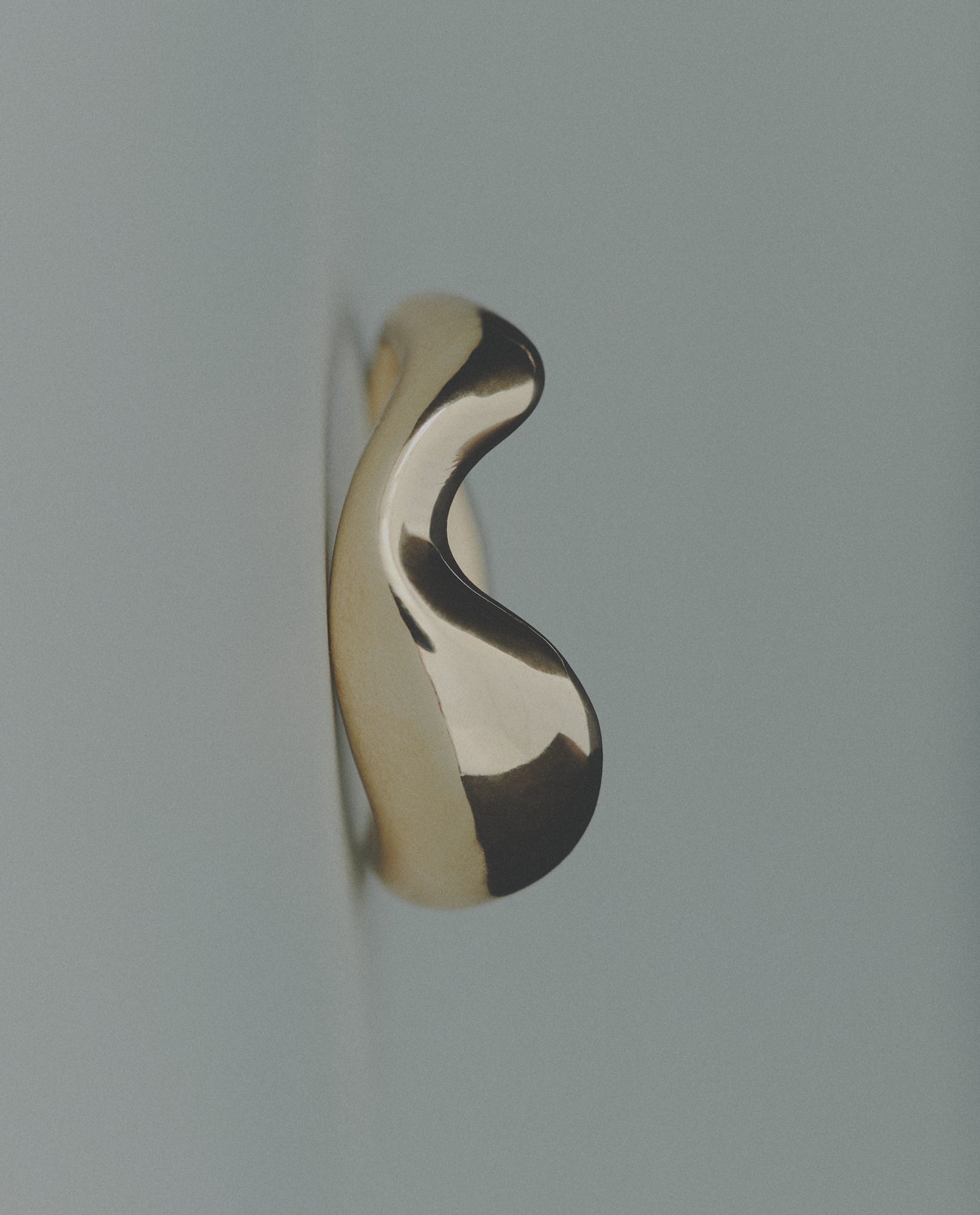 Wavy bold gold ring on gray background