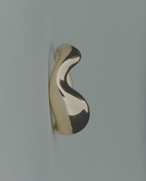Wavy bold gold ring on gray background