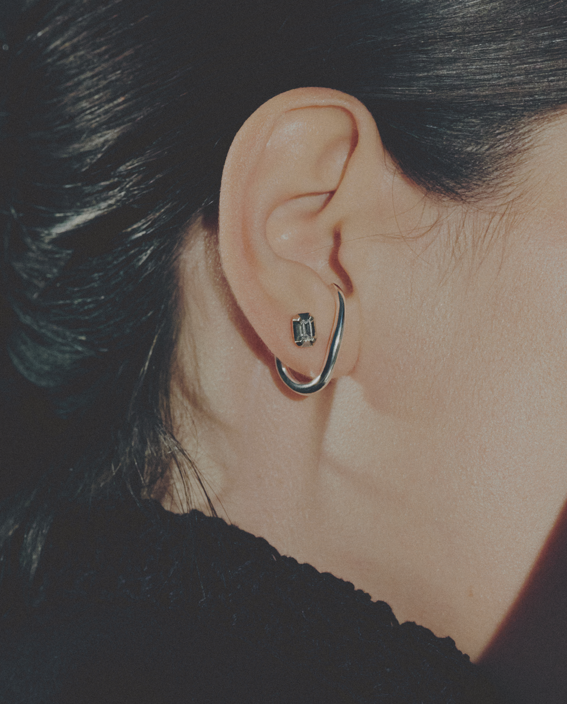 Close-up of an ear wearing a silver cuff earring and a small diamonds stud earring.