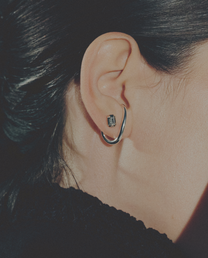 Close-up of an ear wearing a silver cuff earring and a small diamonds stud earring.