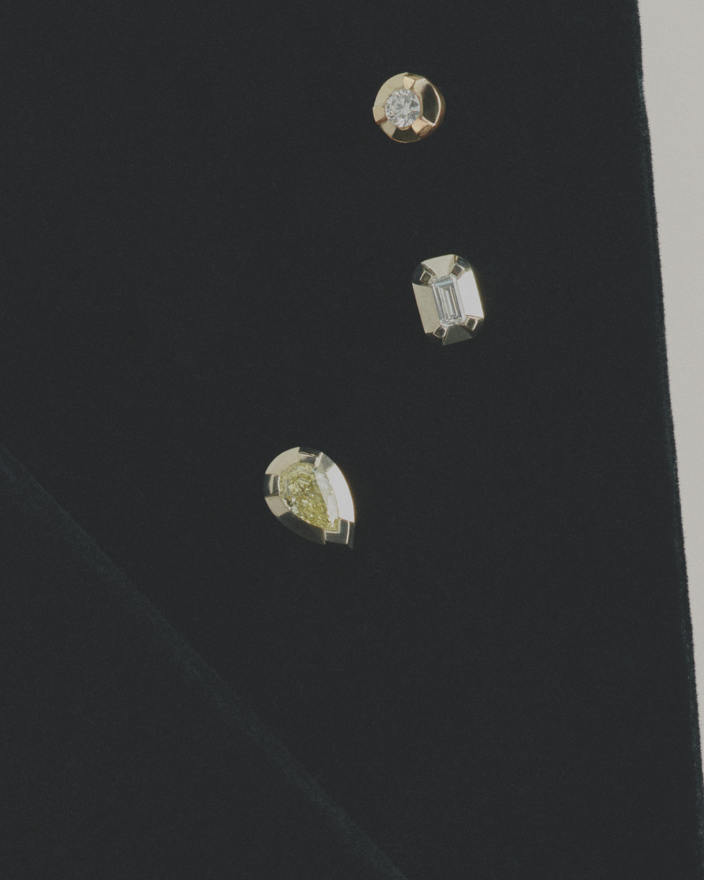 Close-up of three diamond earring studs on a black background