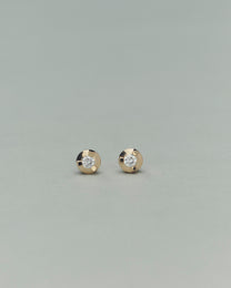 Pair of gold earrings with embedded diamonds on a light gray background