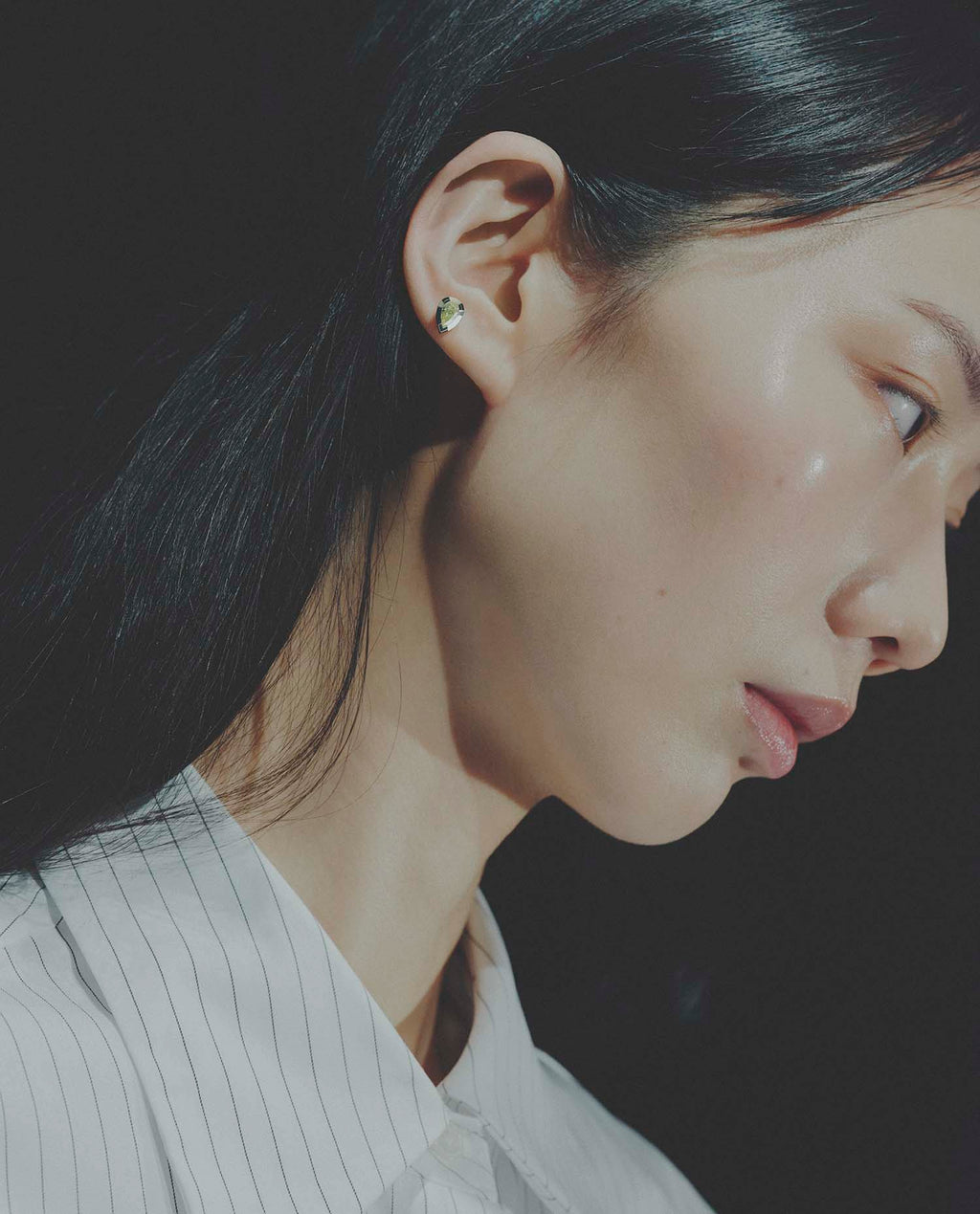 Close-up of a person wearing a small earring with a dark background