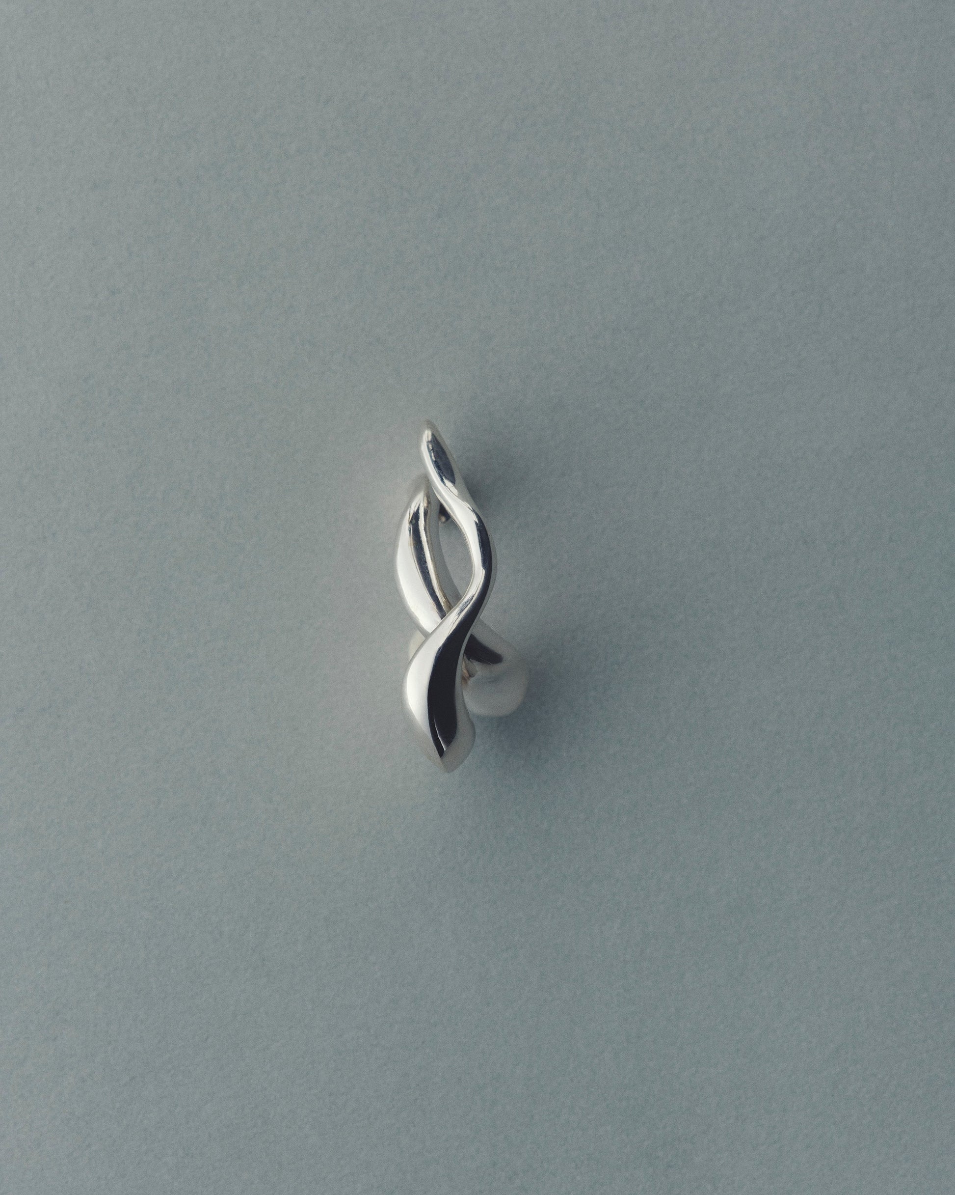 Silver earring on a gray background