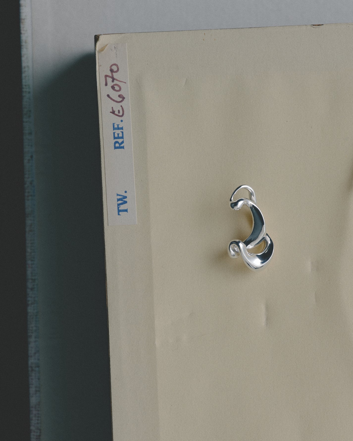 Silver ear cuff on a beige card with a label