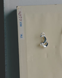 Silver ear cuff on a beige card with a label