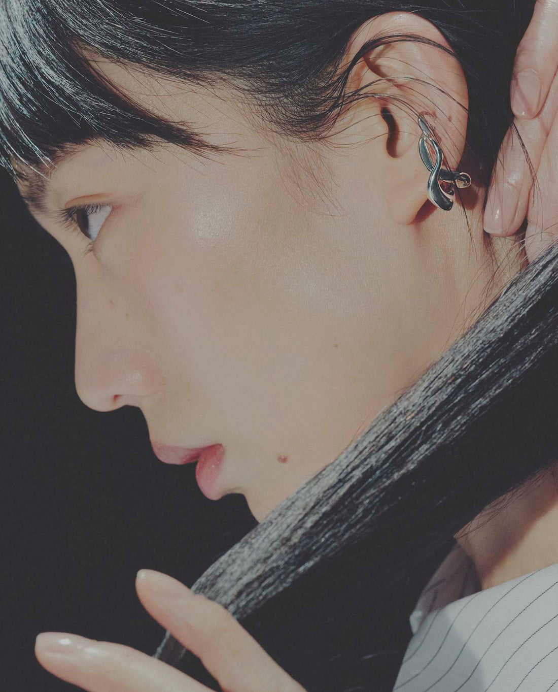 Close-up of a person wearing an ear cuffwith a dark background