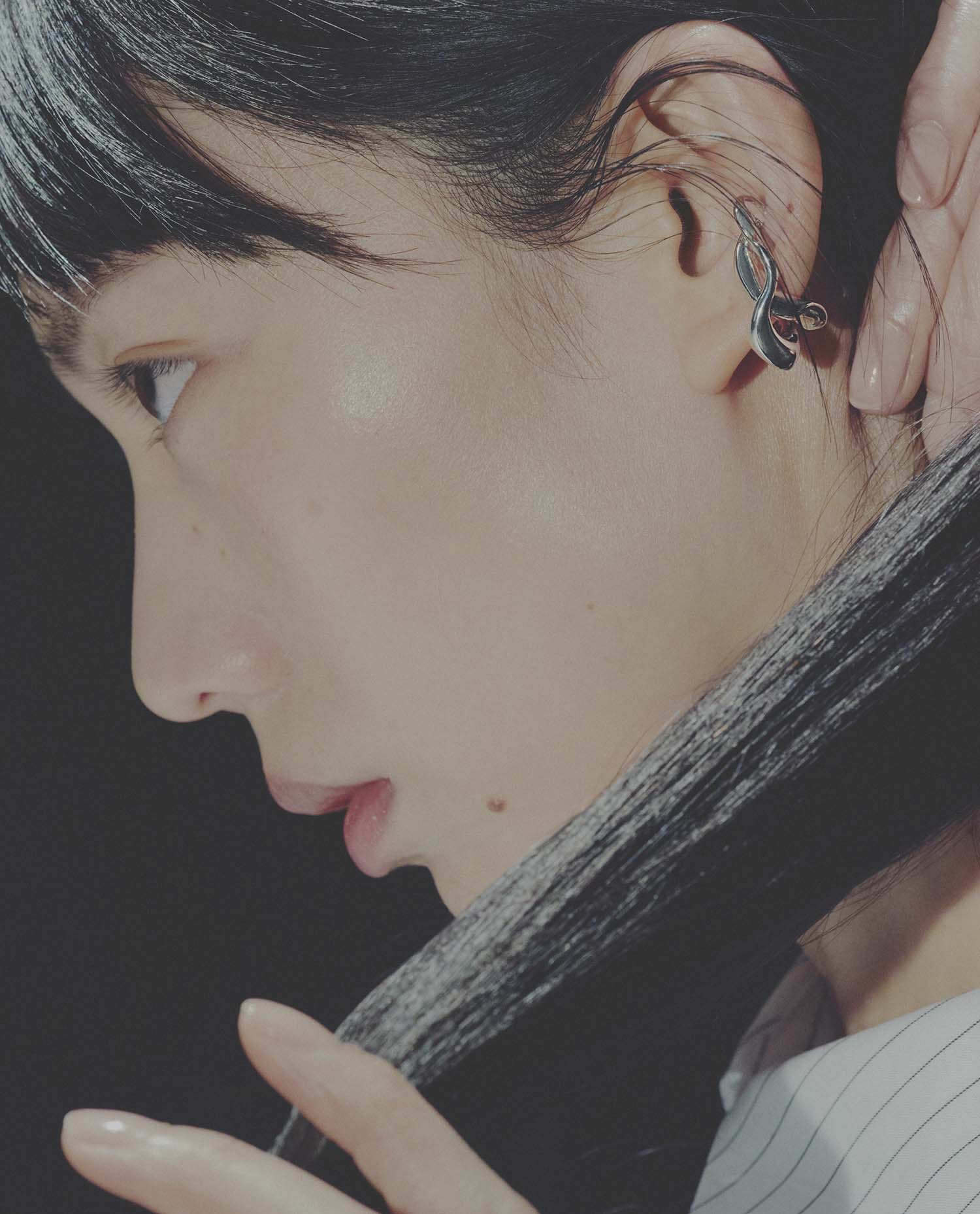 Close-up of a person wearing an ear cuffwith a dark background