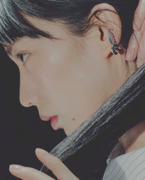 Close-up of a person wearing an ear cuffwith a dark background