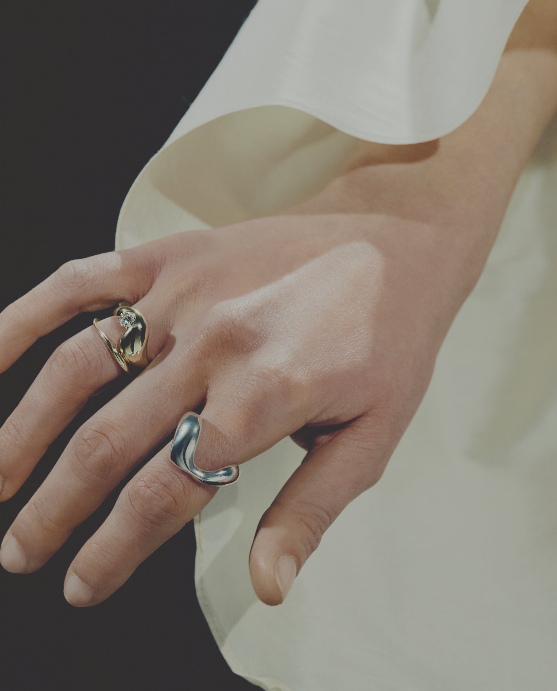 Close-up of hand wearing three rings with a blurred background