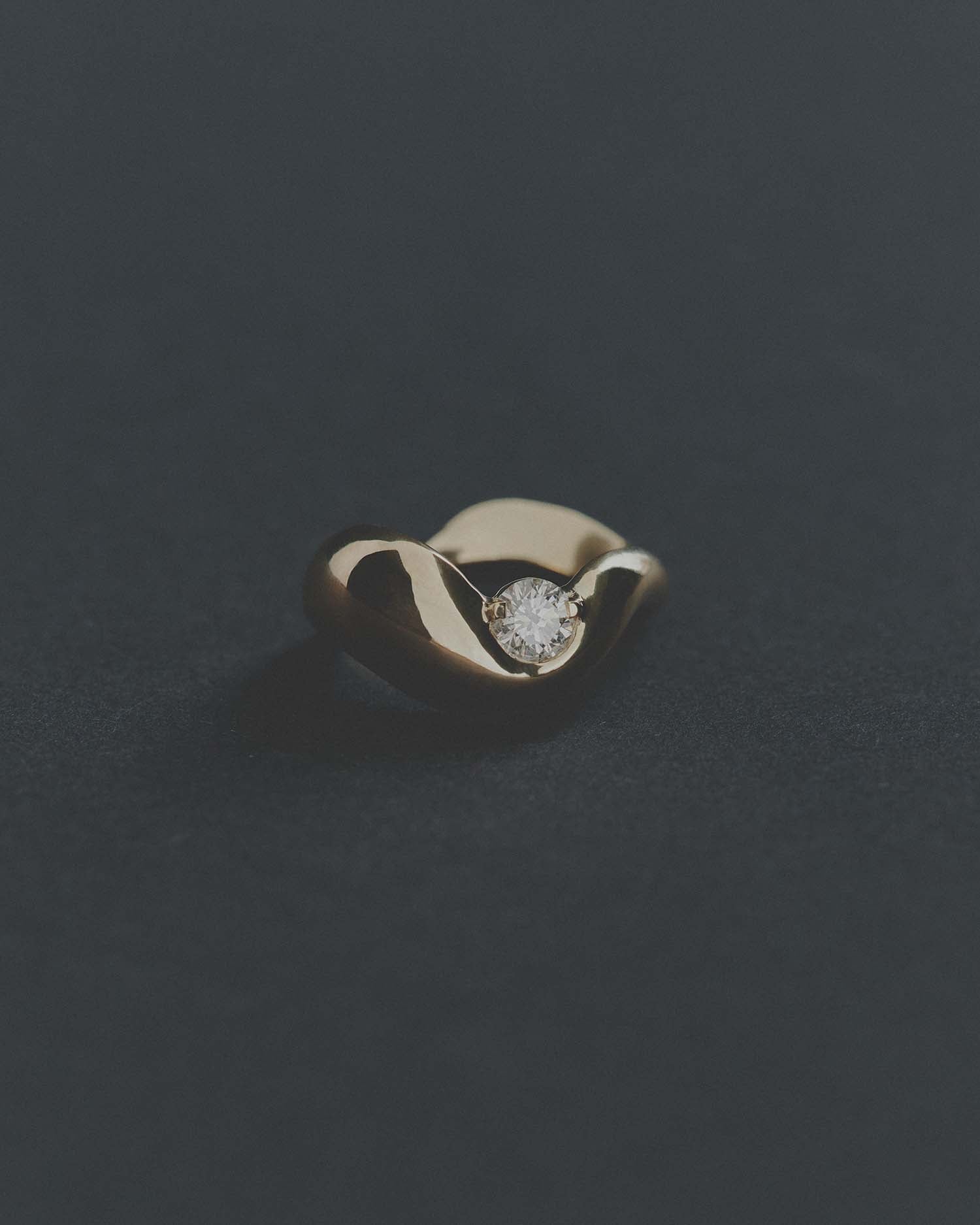 Gold ring with a diamond on a dark gray background