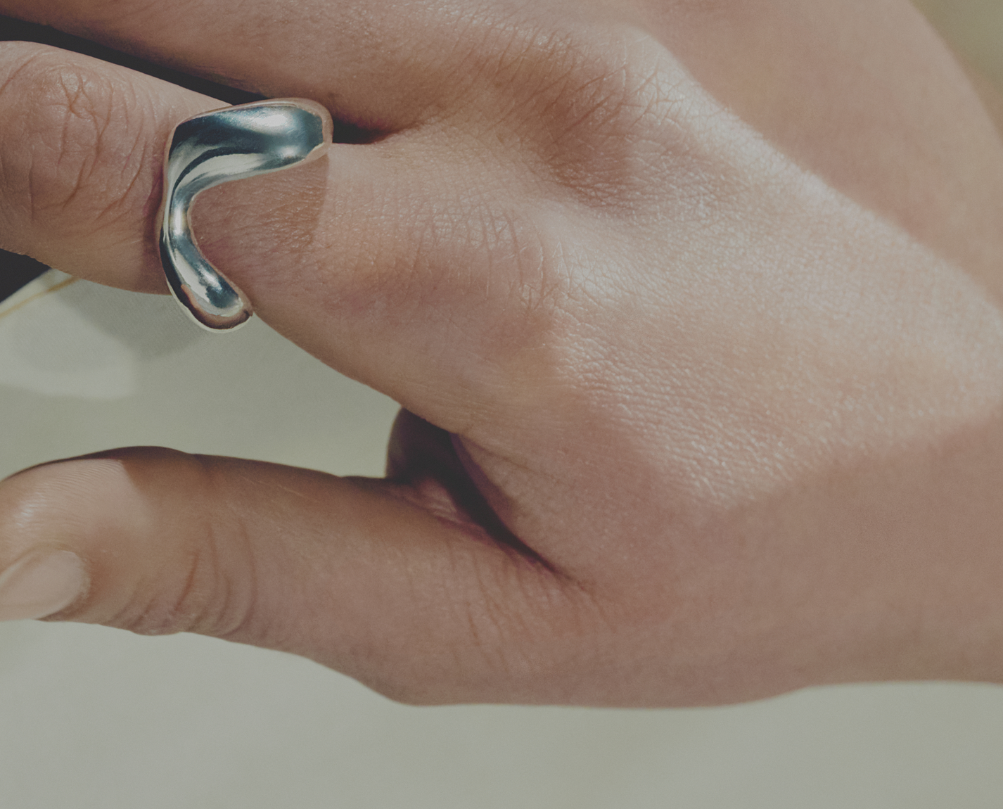 Silver ring on a finger with a neutral background