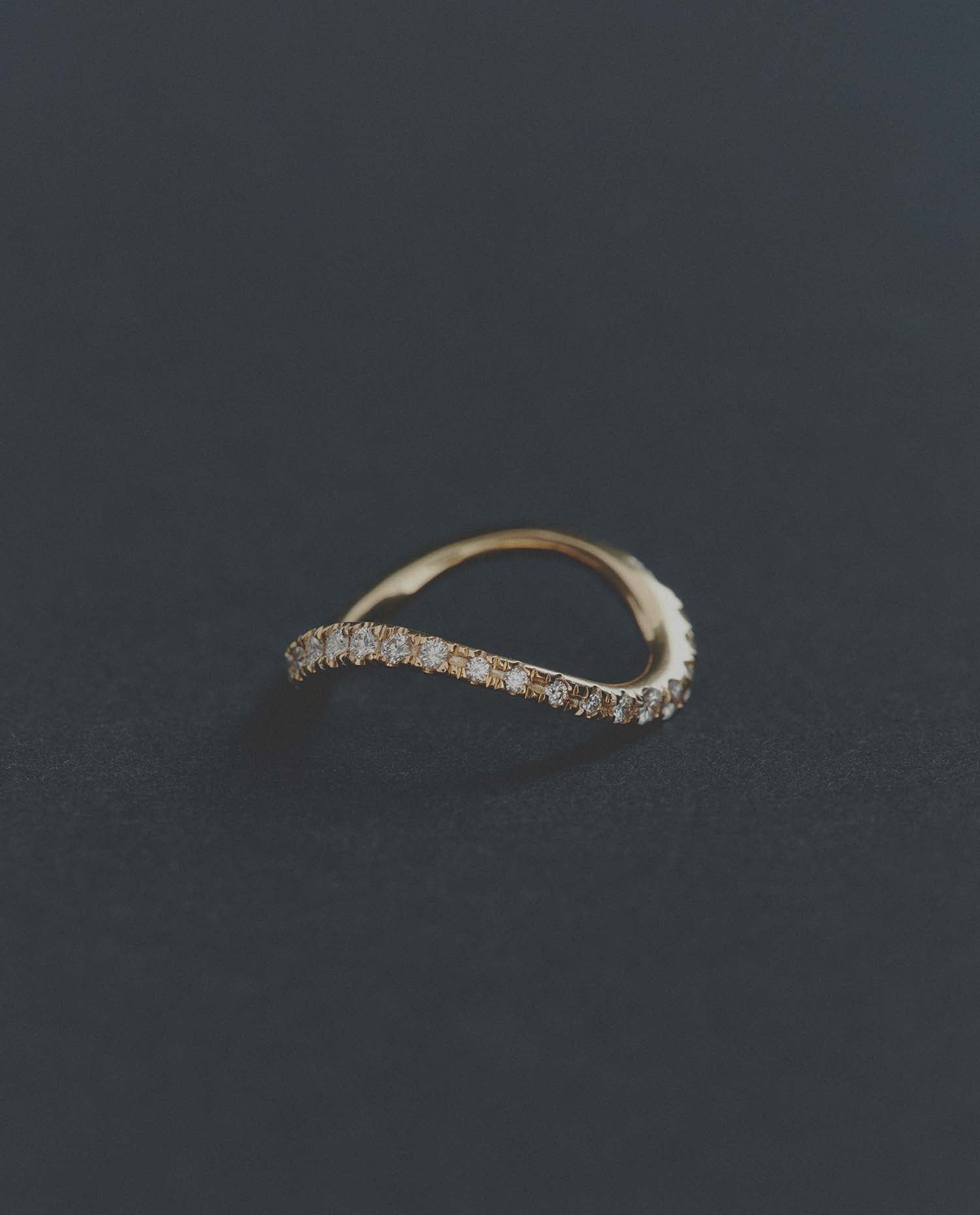 Delicate gold ring with small diamonds on a dark gray background
