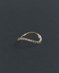 Delicate gold ring with small diamonds on a dark gray background