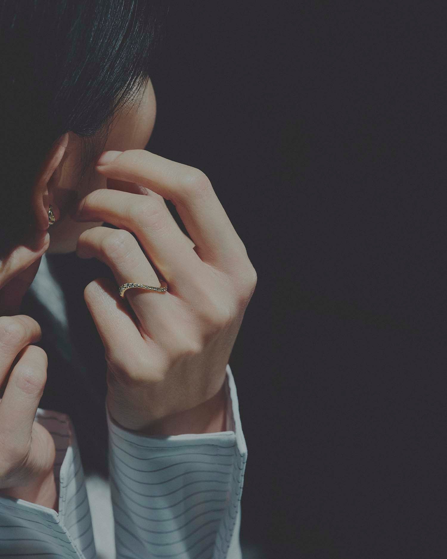 Close-up of a person's hand with a ring on a dark background