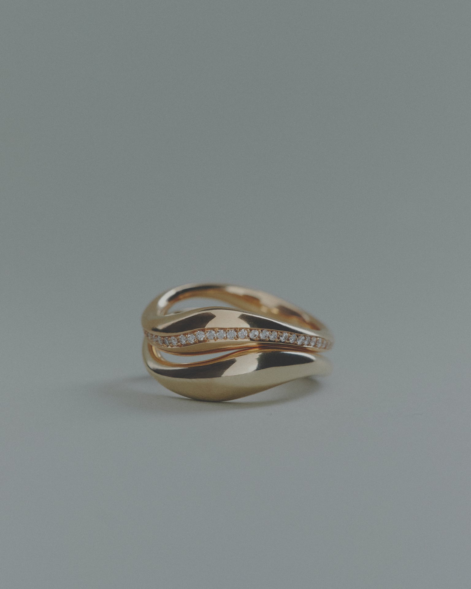 Two gold rings, one with small diamonds, on a gray background