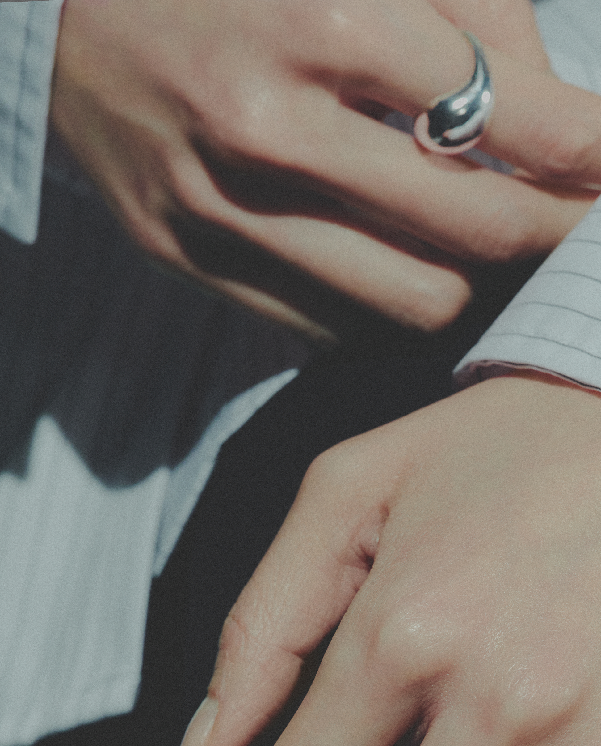 Close-up of a hand wearing a silver ring with a blurred background