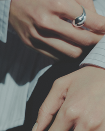 Close-up of a hand wearing a silver ring with a blurred background